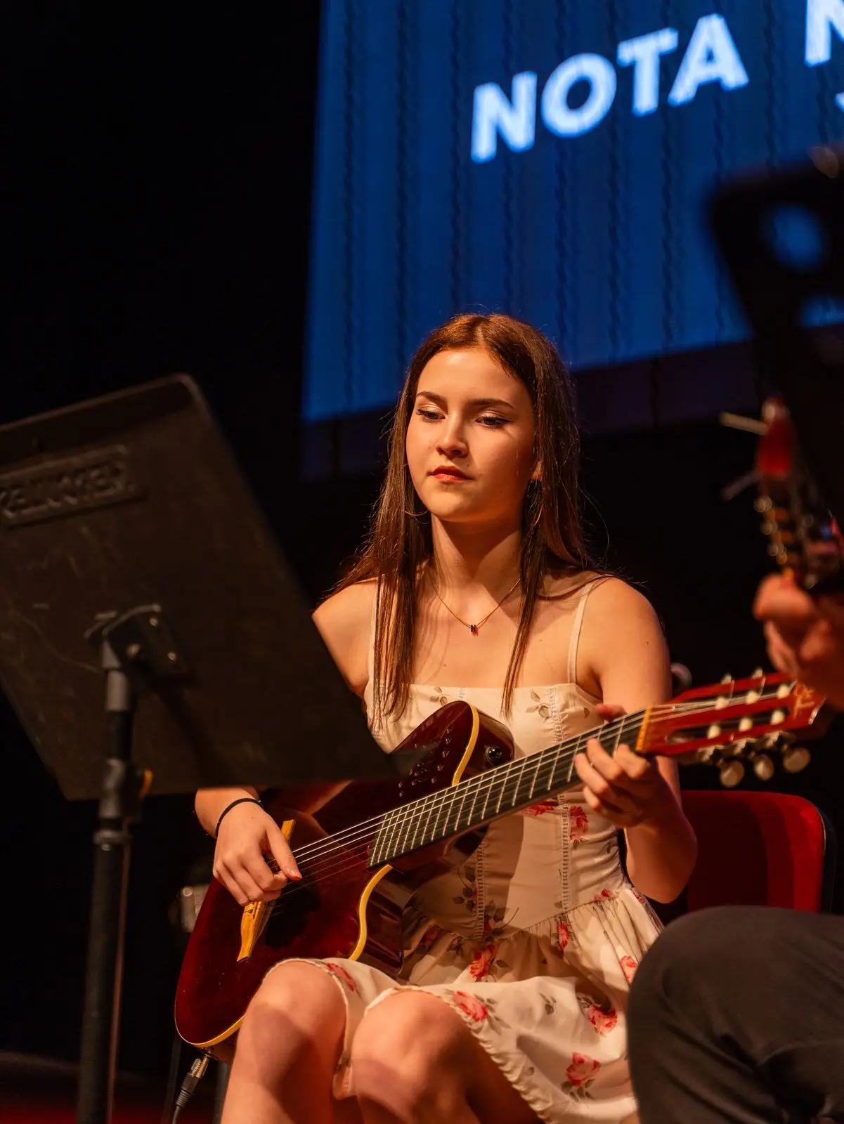 Sahnede klasik gitar çalan bir öğrenci
