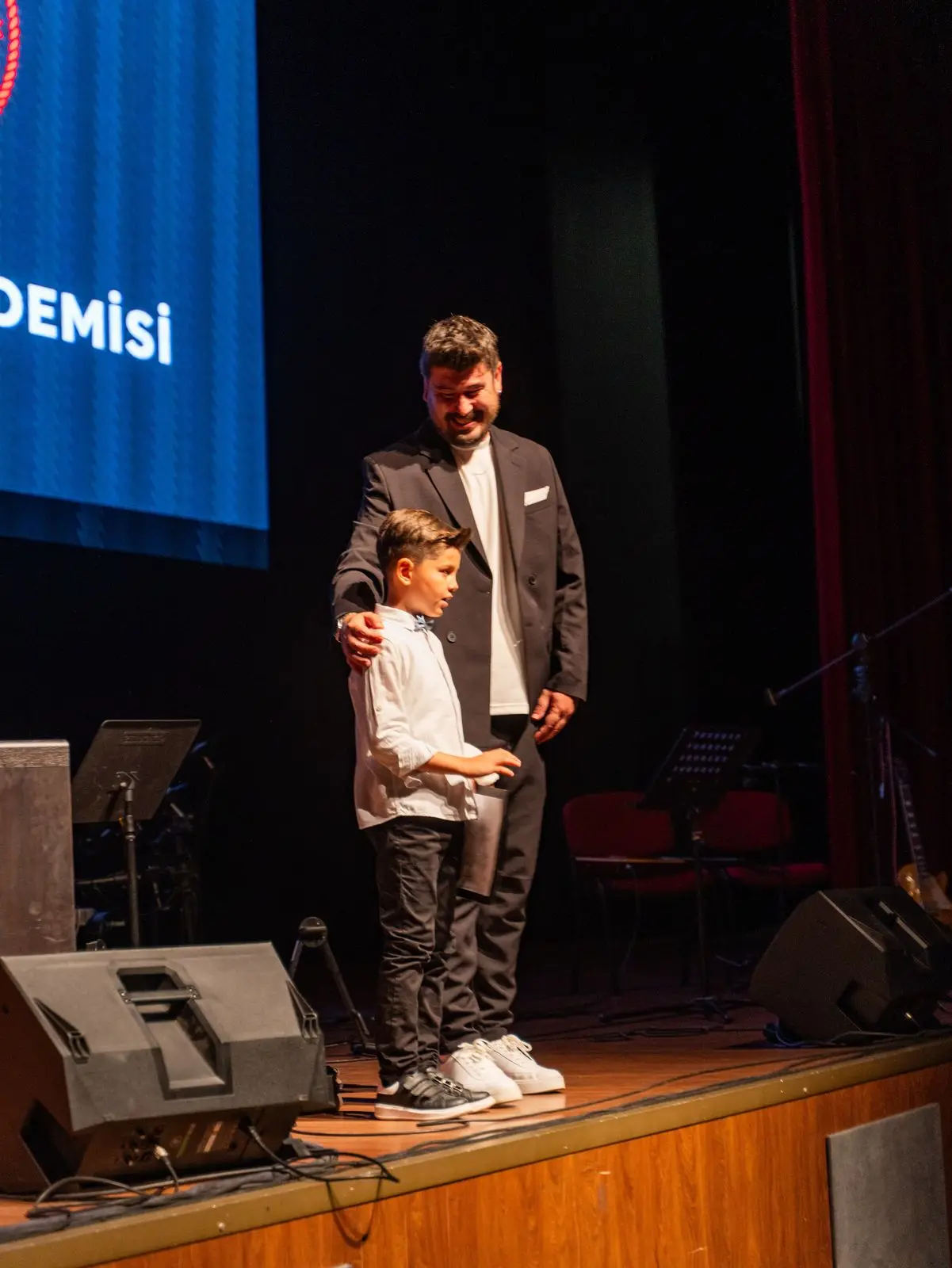 Eğitmeniyle birlikte sahnede şarkı söyleyen küçük öğrenci