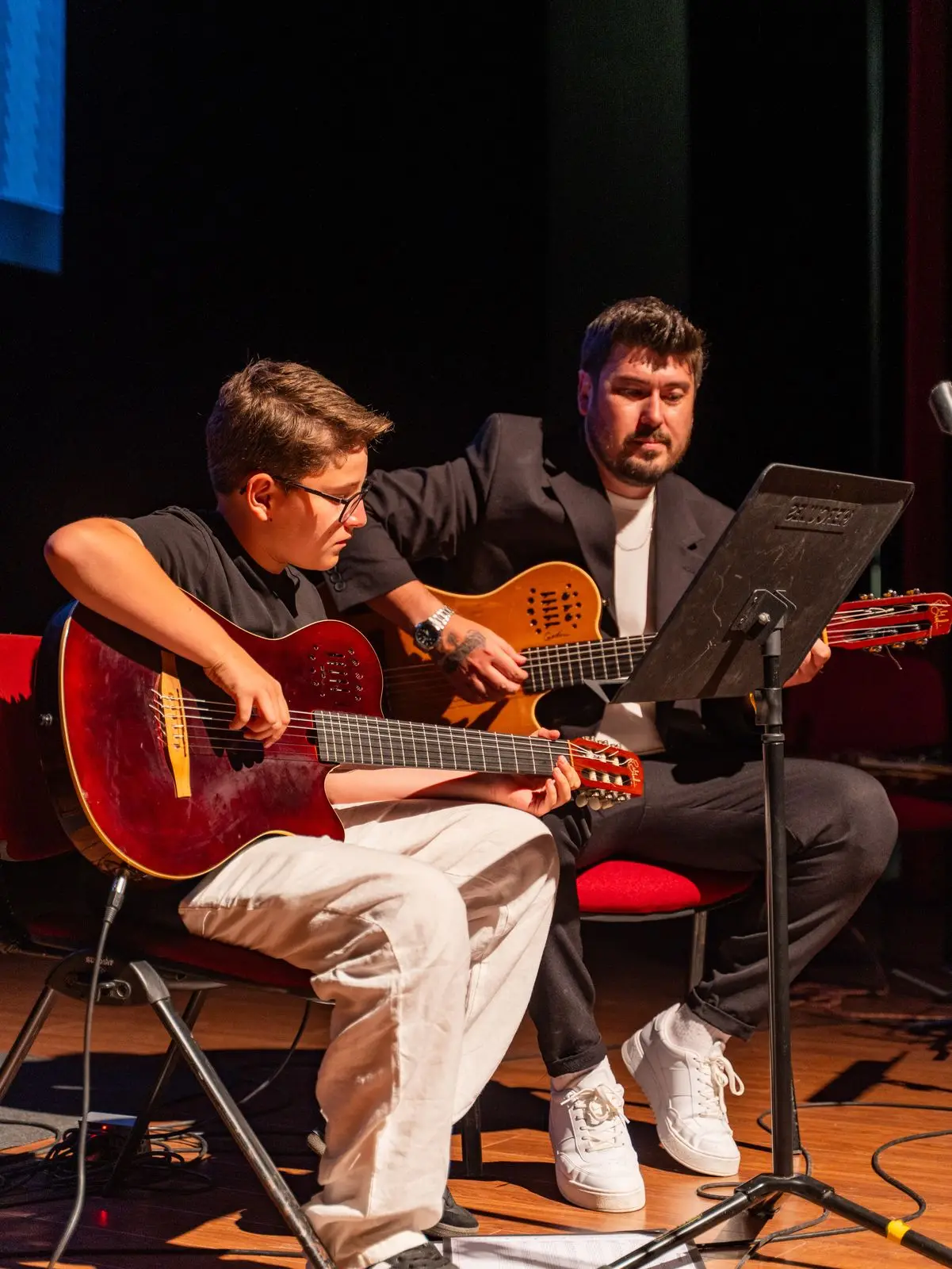 Eğitmeniyle birlikte gitar çalan öğrenci