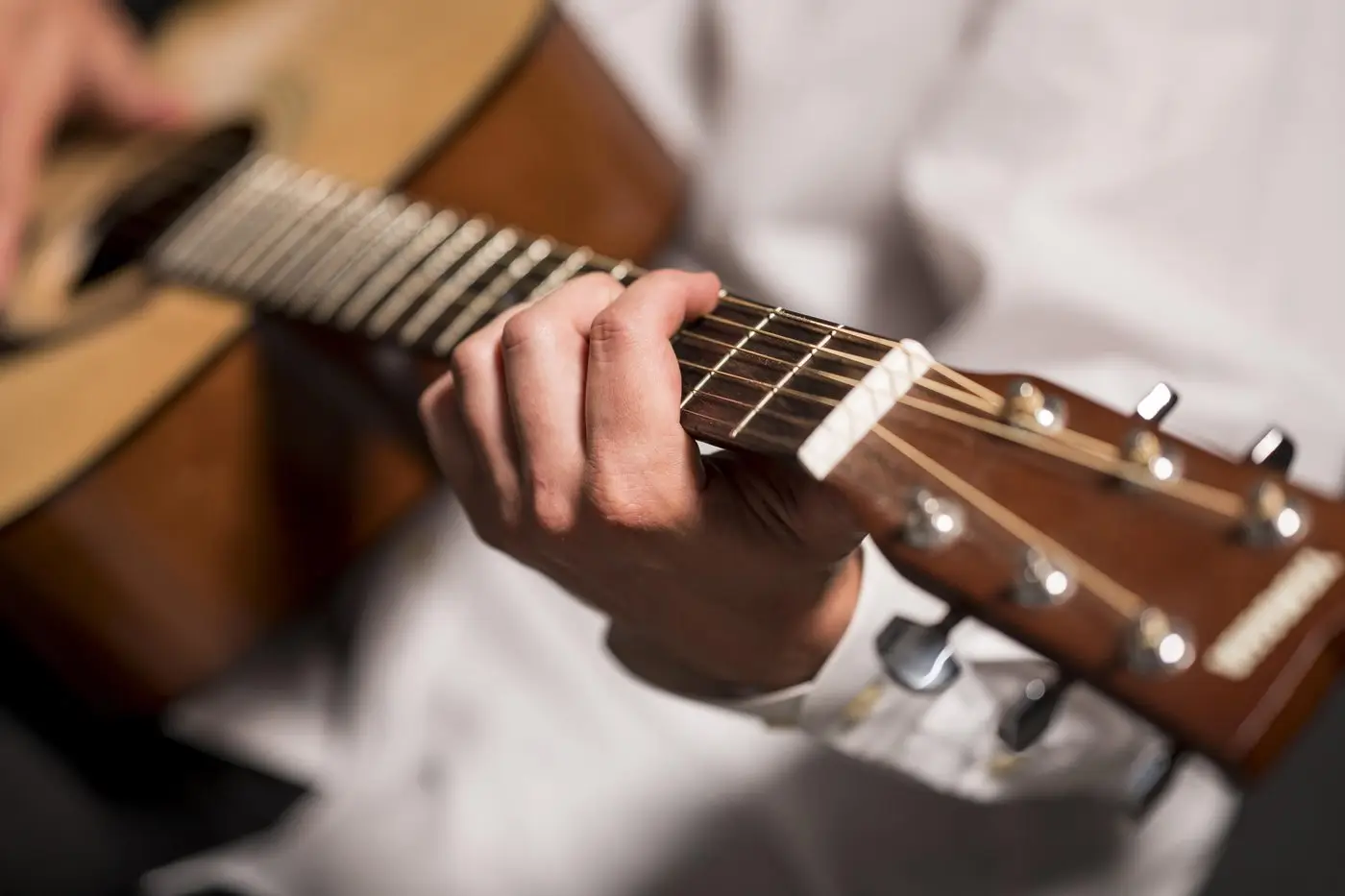 Gitarın teline basan ve tezene tutan eller